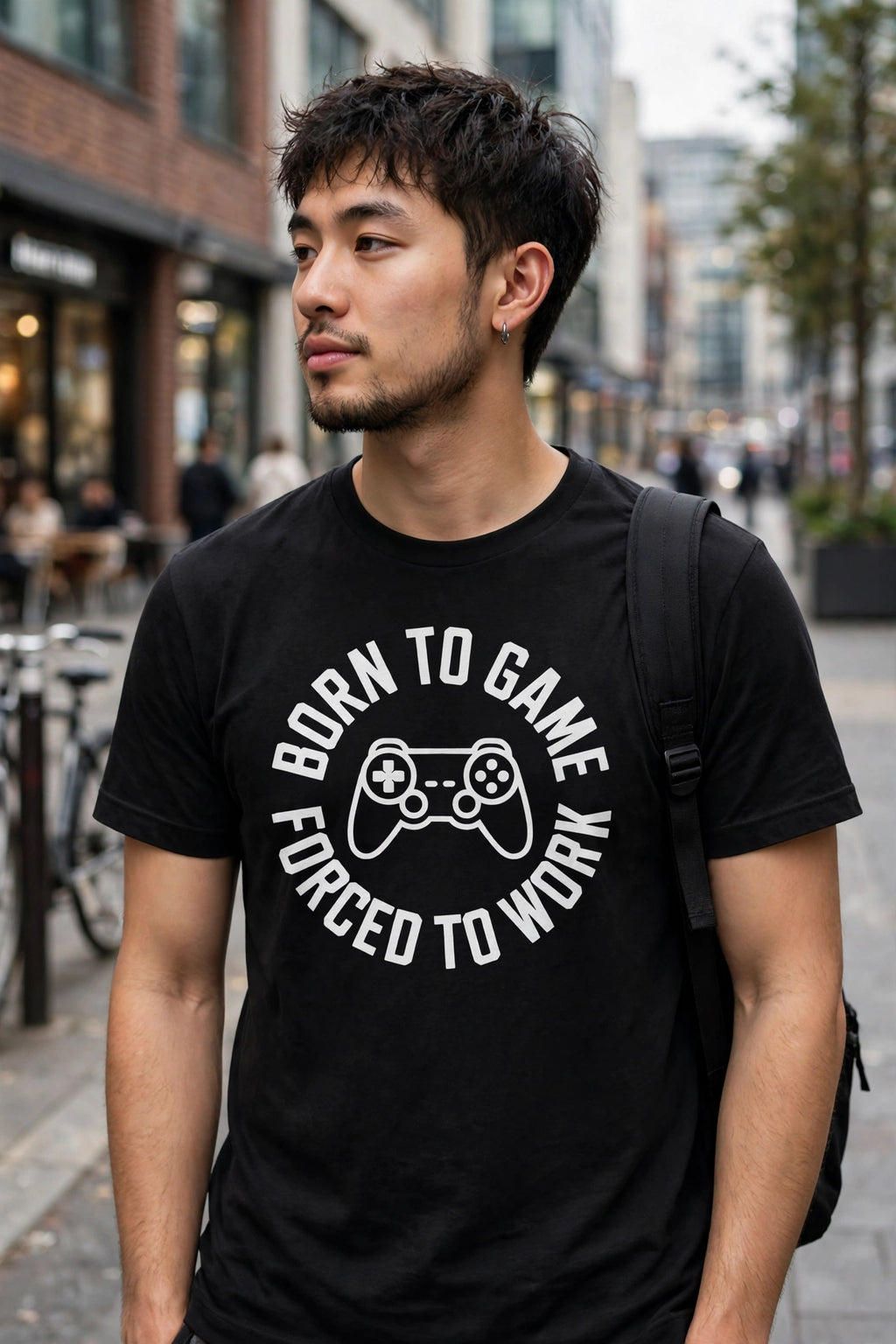 Person wearing the Born To Game, Forced To Work black unisex t-shirt on a city street