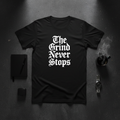 Flat lay of The Grind Never Stops black tee with hustle accessories